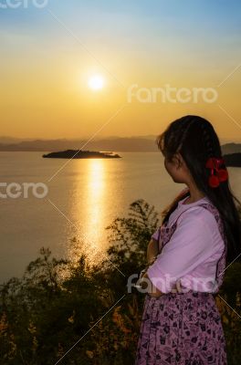 Young woman watching the sunset over the lake