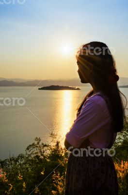 Young woman watching the sunset over the lake
