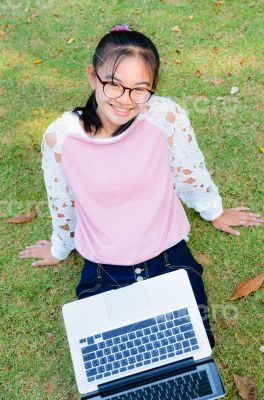 Cute girl is happy with notebook on grass