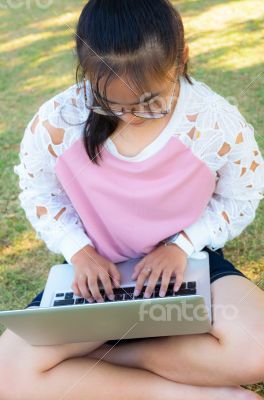 Girl working with laptop on grass