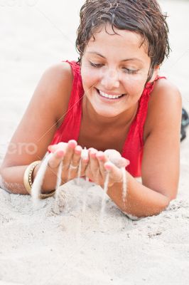 brunet woman in red lying on a sand