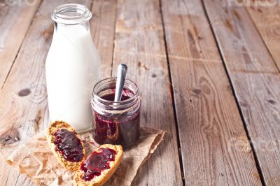 black currant jam in glass jar, milk and crackers