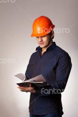 Builder in protective helmet reading papers