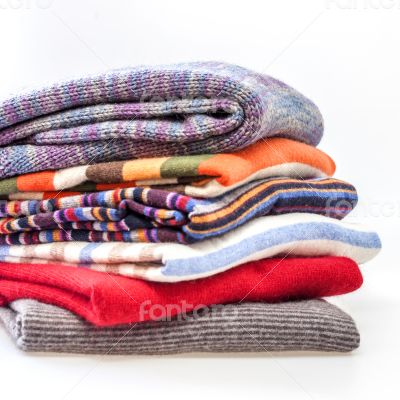 Pile of woolen jumpers of various colors and textures 