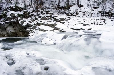 Ice covers rocks in a slow motion river in the winter 