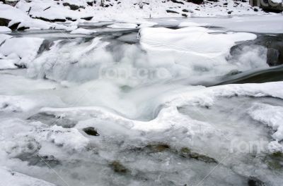 Ice covers rocks in a slow motion river in the winter 