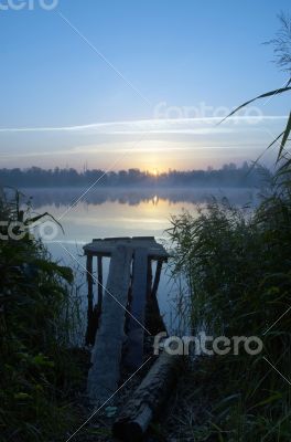 Foggy morning landscape in the autumn park near the lake.