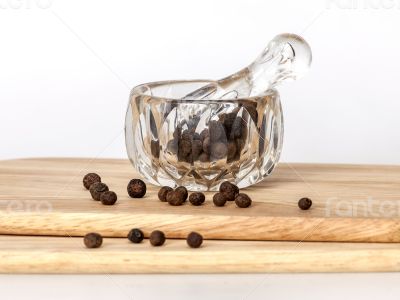Black pepper in a transparent mortar with a pestle