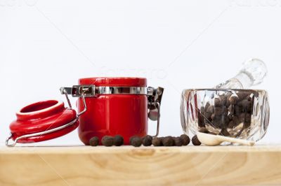 Black pepper in a transparent mortar and container for spices