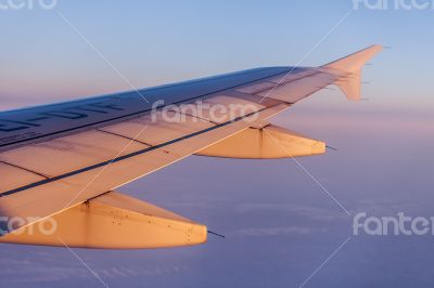 Flight at sunrise. The wing of the plane