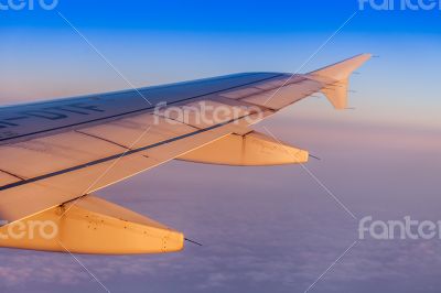 Flight at sunrise. The wing of the plane