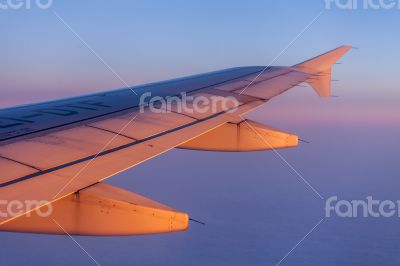 Flight at sunrise. The wing of the plane