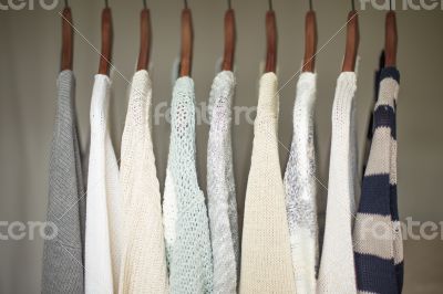 A row of warm and soft sweaters for women on wooden hangers in a