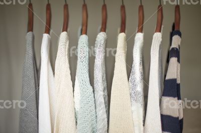 A row of warm and soft sweaters for women on wooden hangers in a A row of warm and soft sweaters for women on wooden hangers in a