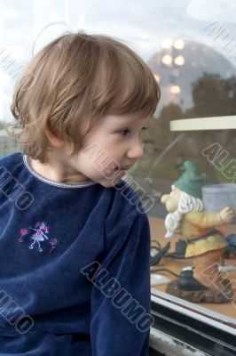 Small girl looking at shop window.