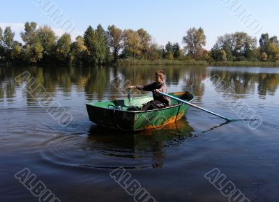Boy in boat with oars on still river