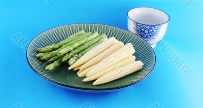 Fresh asparagus shoots and corn on a plate