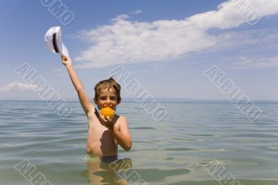 The boy with an orange on a background of the sea