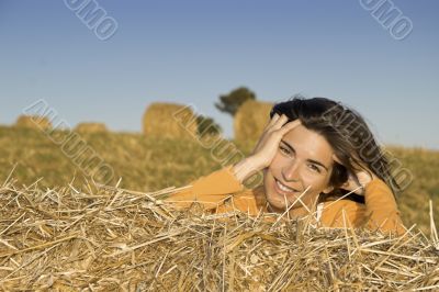 Beautiful woman in a field with hay bales