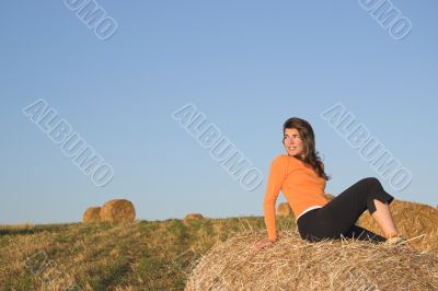 Beautiful woman in a field with hay bales