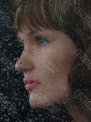 Girl looks thru waterdropped widow glass