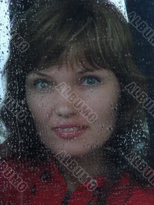 Girl looks thru waterdropped widow glass