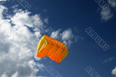 Orange kite next to the clouds