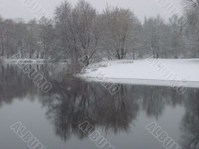First season snowfall on riverside water