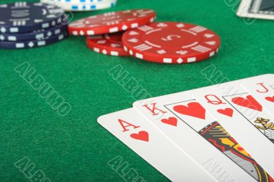casino tokens and a royal flush over green