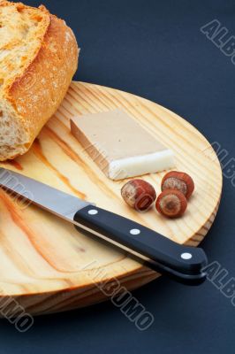 Pate, bread, hazelnuts and knife on wood plate
