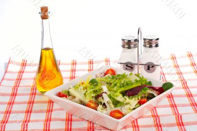Oil bottle, green salad, salt and pepper