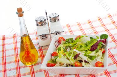 Oil bottle, green salad, salt and pepper