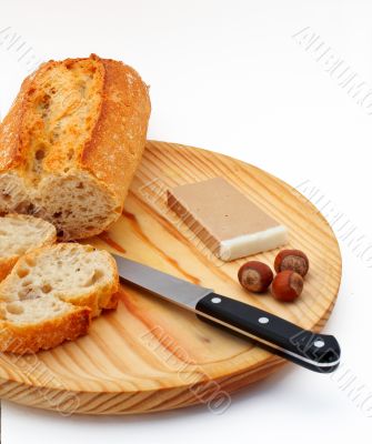 Pate, bread, hazelnuts and knife on wood plate
