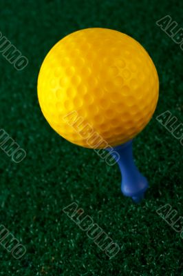 Yellow golfball and blue tee