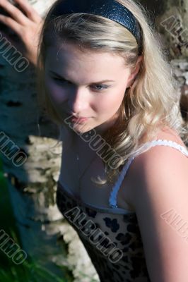 The young girl about a tree in a wood