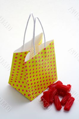 Yellow shopping bag and pieces of red licorices