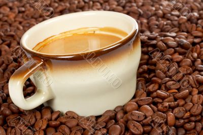 Coffee beans around cup of coffee
