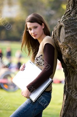 leaning against a tree with notebook