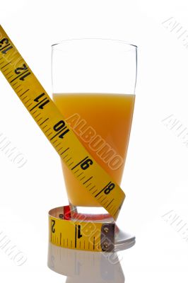 A glass of juice with a metric coiled tape
