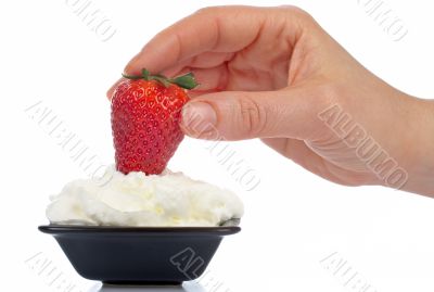 Woman hand strawberry over cream