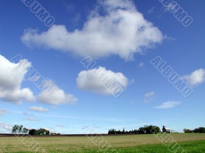 wide shot farmland with blue sky and clouds