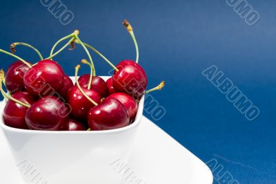 multiple cherries in a white bowl