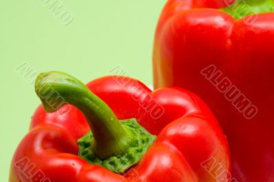 close-up of two red peppers with green background
