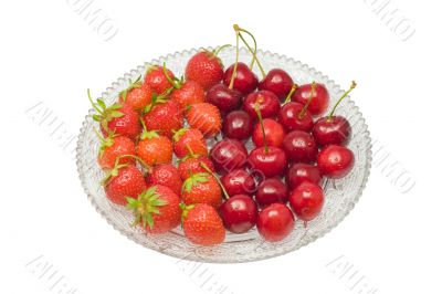 Strawberries and cherries on glass dish, isolated