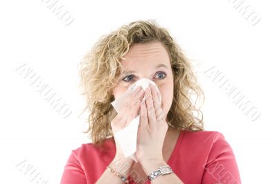 Young blond girl sneezing in the handkerchief
