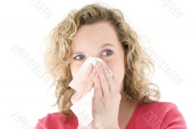 Young blond girl sneezing in the handkerchief
