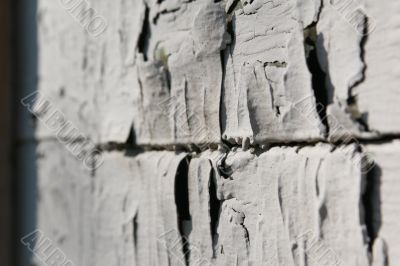 The old cracked grey paint on a wall of the house