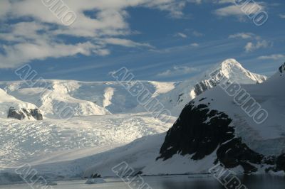 Polar twilight: Glaciated mountains with cloudy blue sky