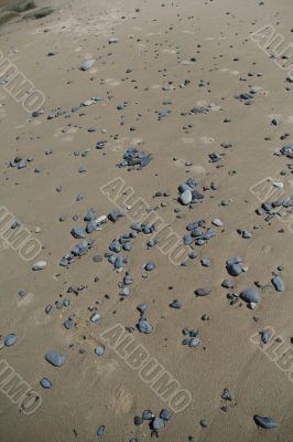 Rounded pebbles scattered along sandy beach