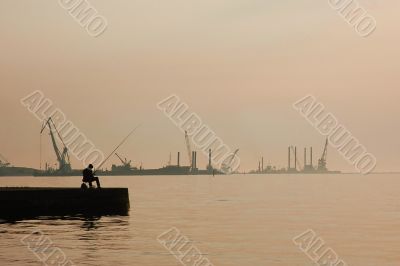 The fisherman on a pier at port on a decline
